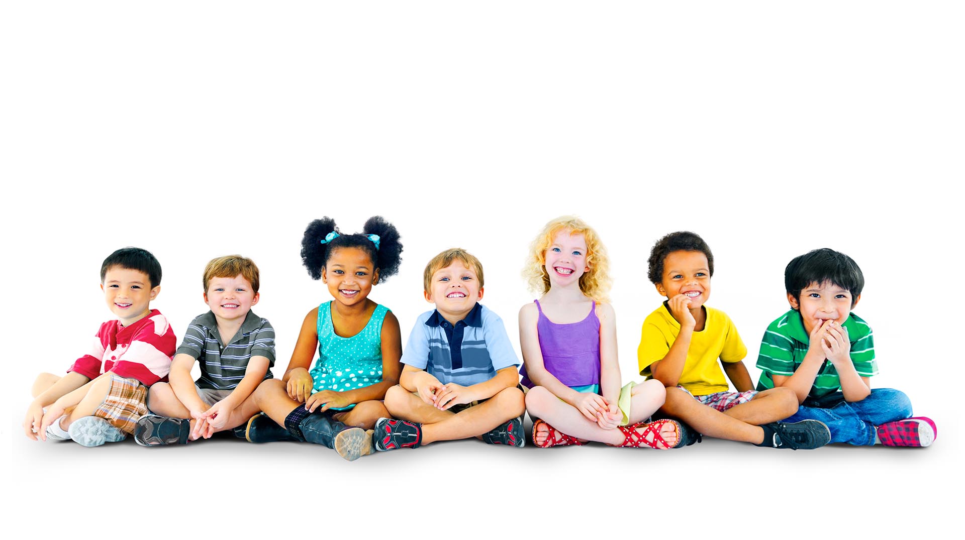 Pediatric Dental Patients. A group of kids sit on the ground smiling at the camera.