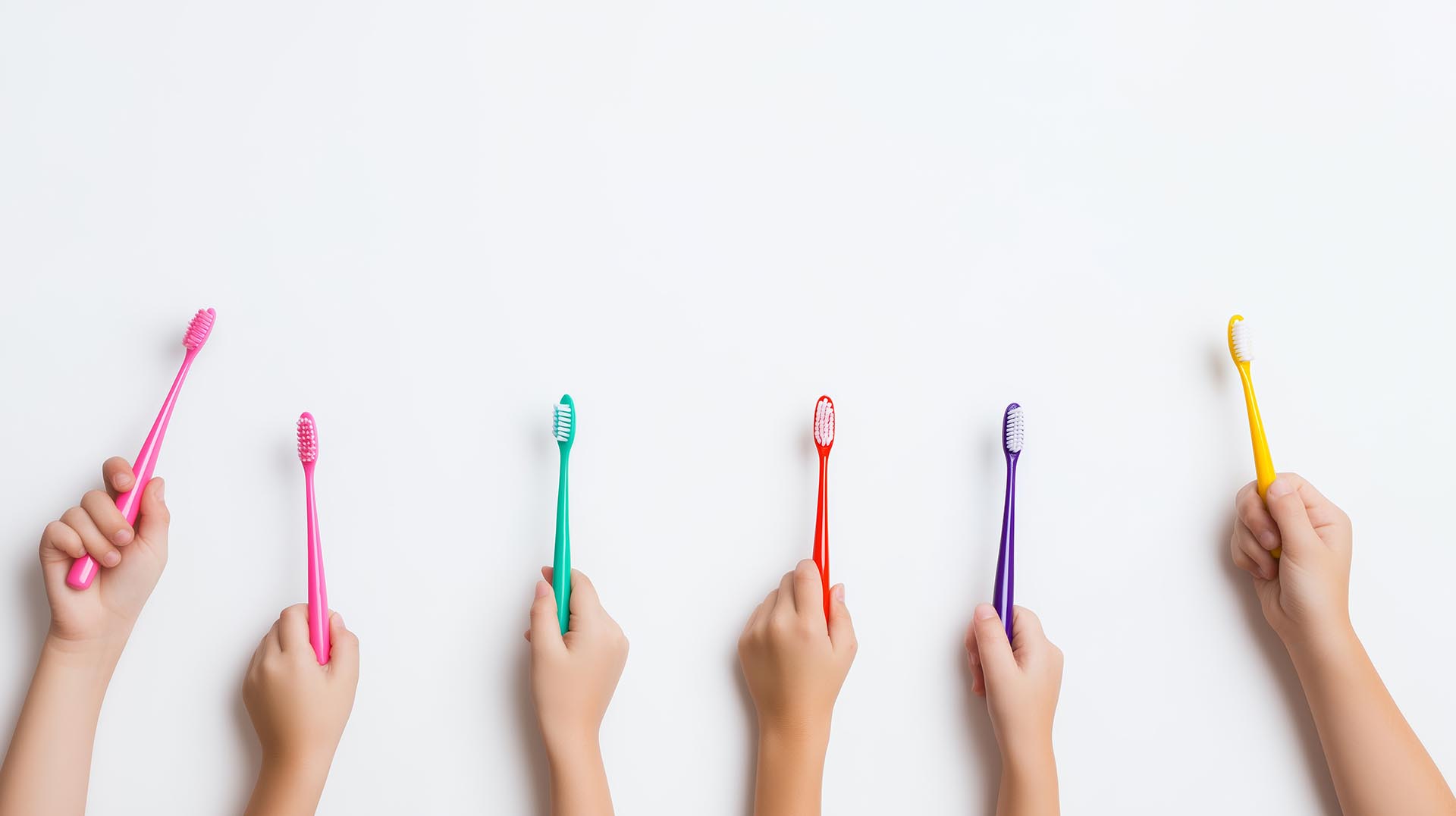 Preventative Pediatric Dental Care. A group of children display their multi-colored tooth brushes.